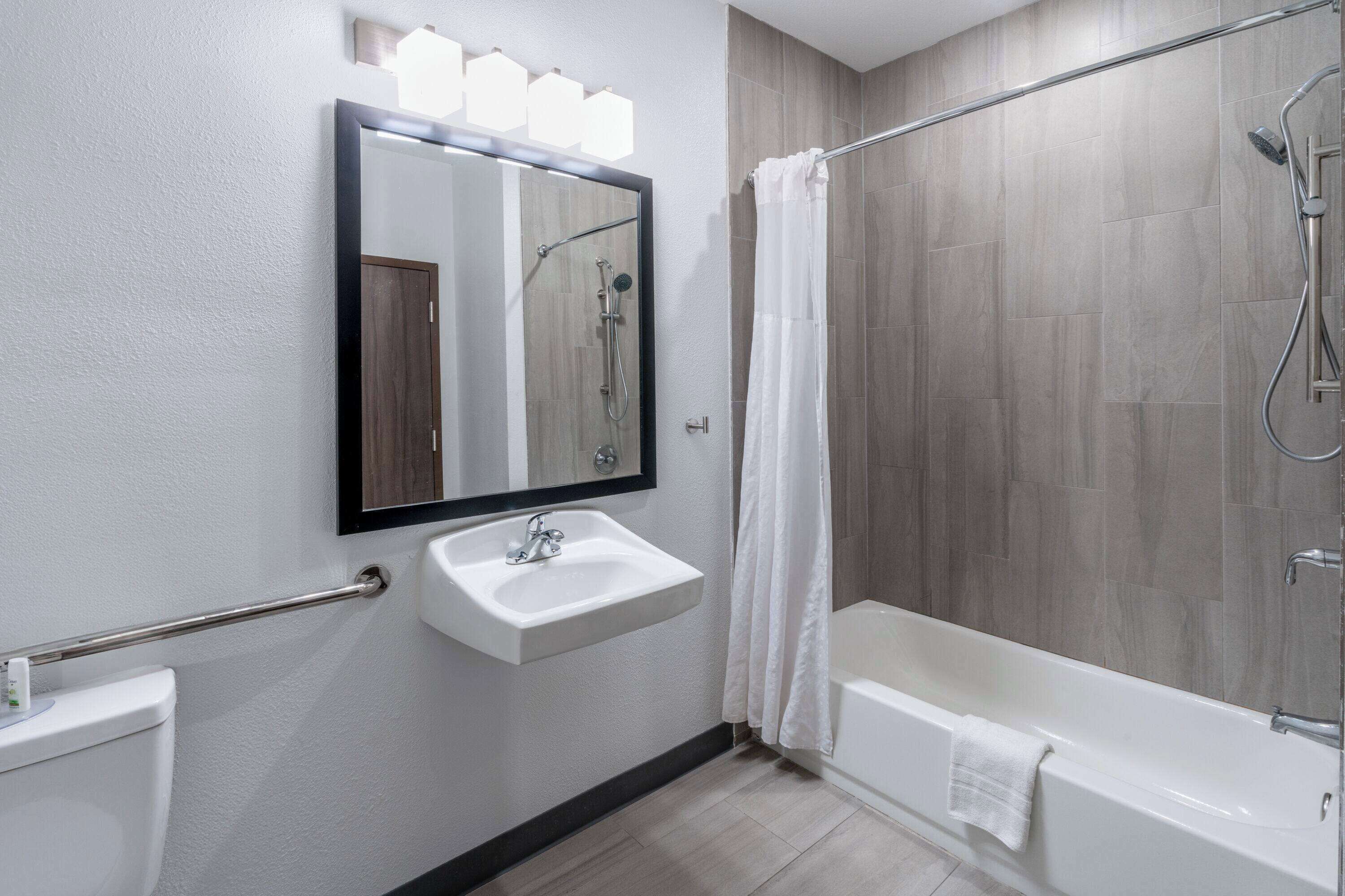 A modern bathroom with a sink, mirror, shower, and bathtub.