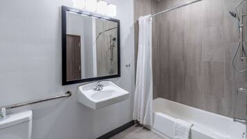 A modern bathroom with a sink, mirror, shower, and bathtub.