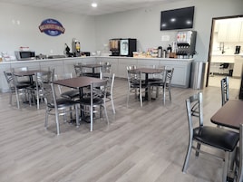 Una zona de desayuno con un letrero de Baymont, una máquina de café y un televisor montado en la pared.