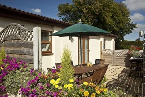 Relax in a patio area with a table and chairs, surrounded by vibrant flowers and a lush tree.