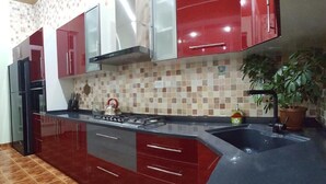A kitchen with red and white cabinets, a black countertop, and a tiled backsplash. - House4you (Tashkent)