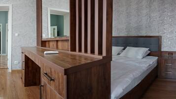 A bedroom with a wooden dresser, a bed with a grey headboard, and a nightstand.