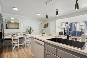 A modern kitchen with a central island, pendant lights, and a view to the outside.