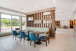 A modern restaurant with a wooden partition, blue upholstered chairs, and a view of the outdoors.