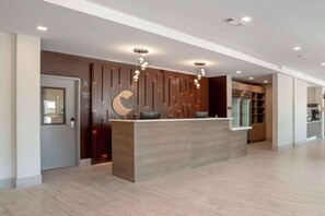 A modern reception desk with a wooden finish, a large crescent moon decoration, and pendant lighting. - Comfort Inn & Suites Destin near Henderson Beach (Destin)