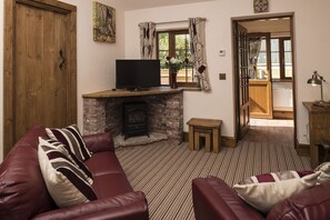 Cozy living room with a fireplace, leather sofa, and television, offering a warm and inviting atmosphere.