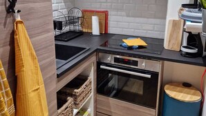 A compact kitchen with wooden cabinets, a built-in oven, and a coffee machine. - Le Portel Plage (Le Portel)