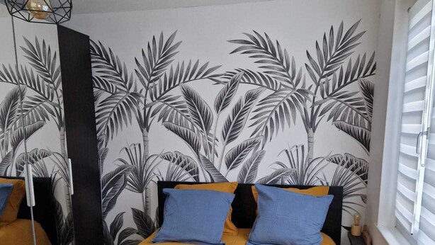 A bedroom with a bed, two pillows, a nightstand, a lamp, and a window with blinds. - Le Portel Plage (Le Portel)