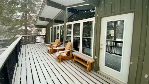 A wooden deck with a covered area, featuring a bench and chairs, and a glass door. - Cozy chalet w/heated pool, hot tub, sauna 3 min dr. to the Blue Mountain village (The Blue Mountains)