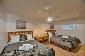 Une chambre d’hôtel avec deux lits, un ventilateur de plafond et des œuvres d’art accrochées aux murs.
