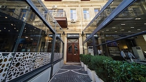 A hotel entrance with a central door, glass railings, and a patterned walkway. - Solo Hotel  (Baku)