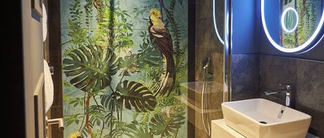 A modern bathroom with a glass-enclosed shower, a white sink, and a mirror with a circular light.