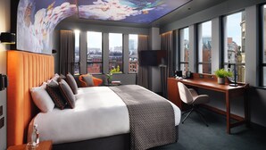 A modern hotel room with a large bed, a desk, and a view of the city through large windows. - Malmaison Manchester Deansgate  (Manchester)