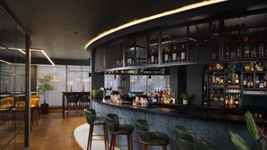 A modern bar area with a curved counter, multiple seating options, and a variety of bottles and glasses on display. - Malmaison Manchester Deansgate  (Manchester)