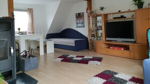 Una sala moderna con una cama de altillo, un televisor de pantalla plana, un mueble de madera y un escritorio.