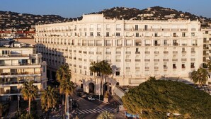 A large, multi-story building with a classical architectural style, featuring numerous windows and balconies. - Apartment with Partial Sea View – Sunset – Cannes Croisette – Palais Miramar (Cannes)