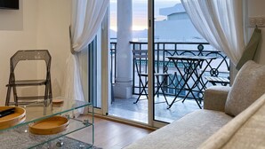 Una sala de estar moderna con una mesa de centro de vidrio, un sofá y un balcón con vista a la ciudad.
