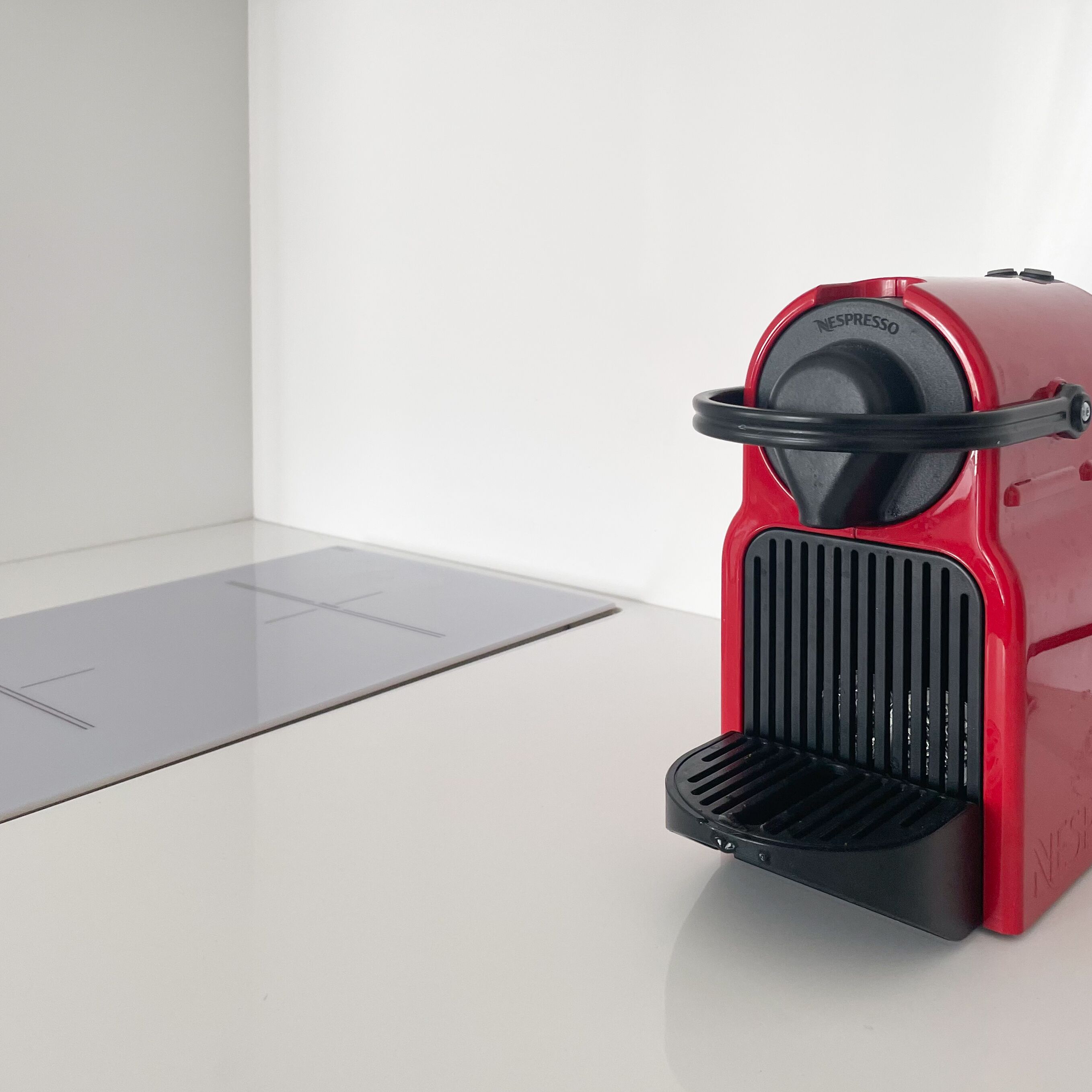 Una macchina da caffè espresso rossa con base nera e un pannello di controllo sulla sommità.