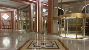 Un vestíbulo con entrada de vidrio, puerta giratoria y piso estampado.