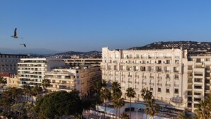 Un hotel de varios pisos con balcones, un patio central y palmeras.