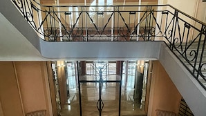 Una escalera de varios niveles con barandillas negras ornamentales y un vidrio en la parte inferior.