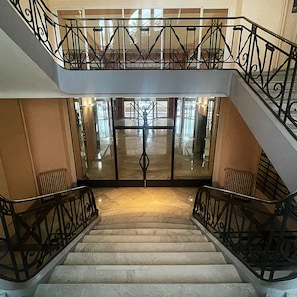 Una scala a più livelli con ringhiere nere decorate e una porta in vetro sul fondo.