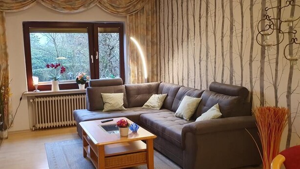 A cozy living room with a sectional sofa, a wooden coffee table, and a radiator. - Vacation apartment Ramke EG (Lilienthal)