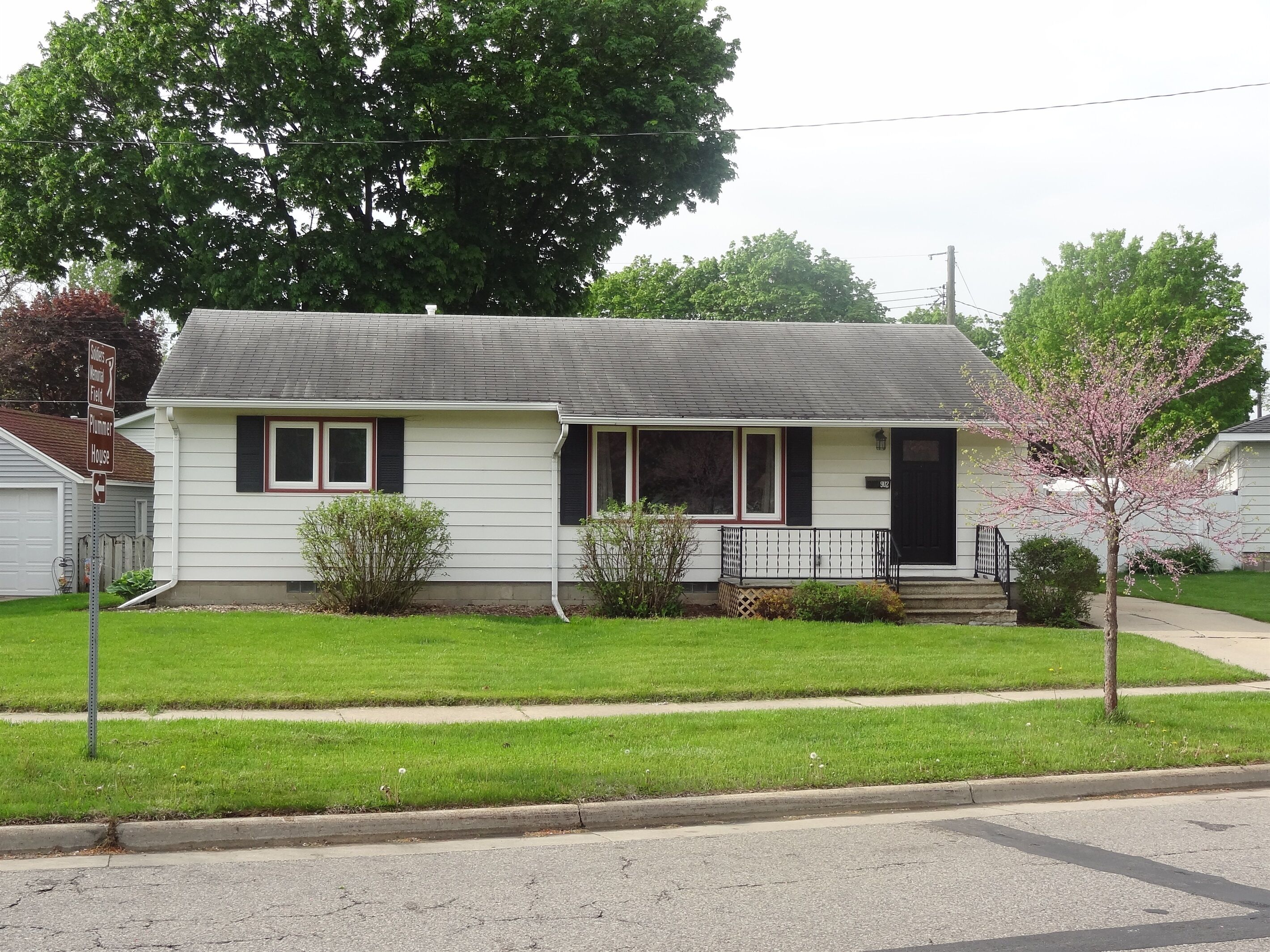 A single-story house with a front porch, a garage, and a small front yard.