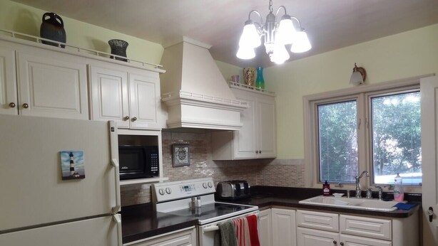 A kitchen with white cabinets, a stove, oven, microwave, and a sink. - 2 Blks St Marys 2 Main Fl Beds Bath CoveredByFaith (Rochester)