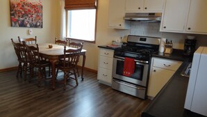 Una cocina con armarios de madera, estufa y una mesa de comedor con sillas.