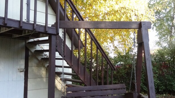 Una escalera de madera que lleva a un edificio blanco con barandilla de metal.