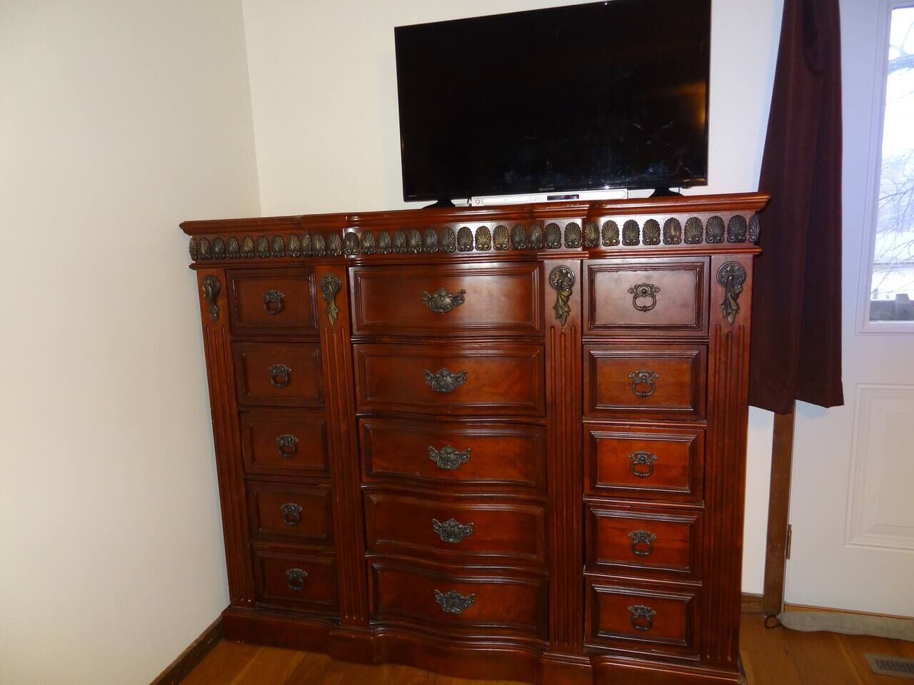Un aparador de madera con varios cajones y un televisor de pantalla plana montado encima.