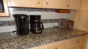 A kitchen with a granite countertop, a coffee maker, a toaster, and wooden cabinets.