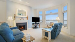 Un salon avec une cheminée, un téléviseur et une vue sur la plage.