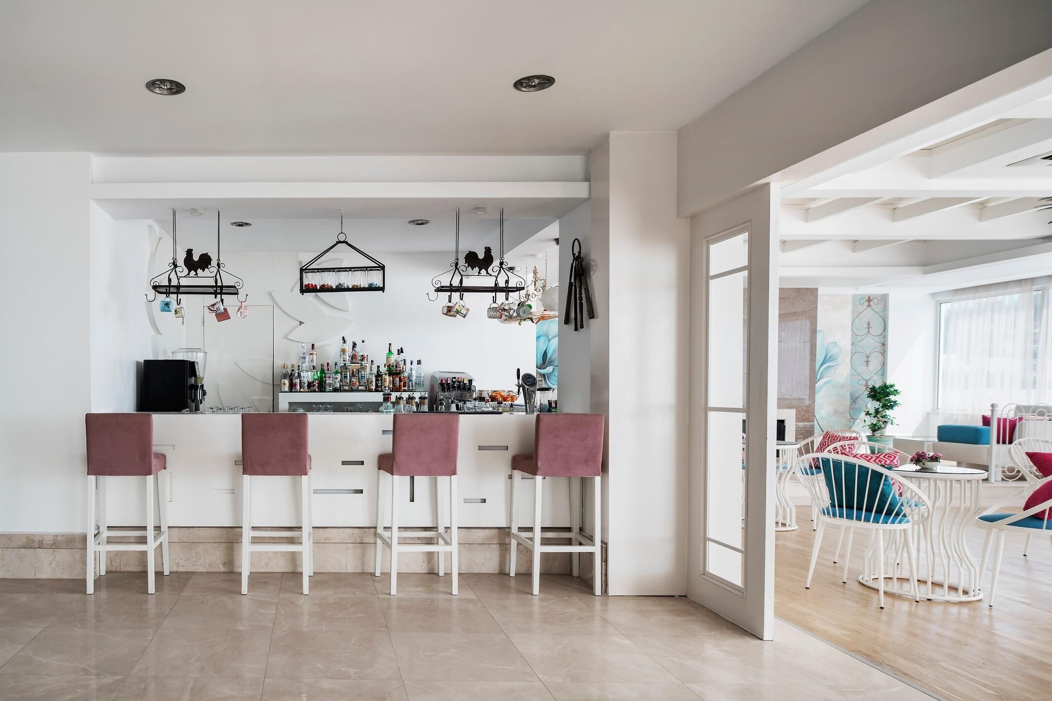A modern kitchen with a bar area, white cabinetry, and hanging decorations.