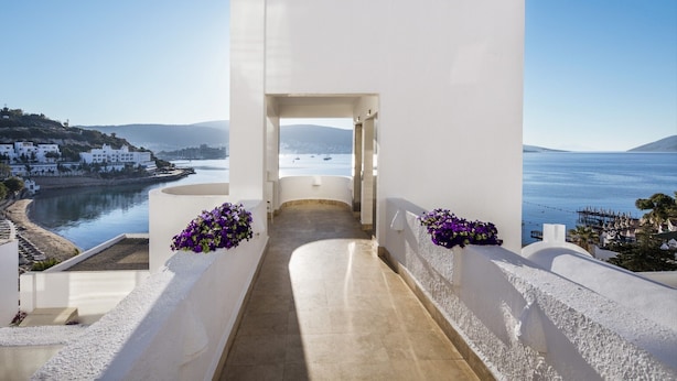 A corridor leading to a balcony with a sea view, white walls, and purple flowers. - Agaya Bodrum +16 Adult Only (Ex.Prive Bodrum) - All inclusive (Bodrum)