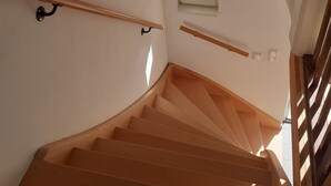 Un escalier en bois, doté d’une rampe et d’une petite fenêtre en haut.
