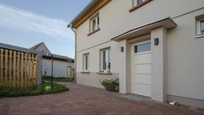 Une maison moderne à deux étages, avec un chemin en briques menant à l’entrée.