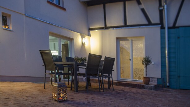 Une terrasse extérieure avec une table et des chaises, une lanterne et une plante en pot.
