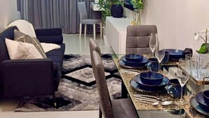 Een moderne woonkamer met een donkere bank, een eettafel met borden en glazen, en een grijze bank.
