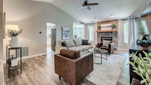 A spacious living room with a fireplace, a ceiling fan, and a large window. - Elegant home in the heart of Westfield! Perfect for family gatherings! (Westfield)