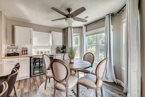 Une cuisine avec un coin repas, un ventilateur de plafond et de grandes fenêtres.