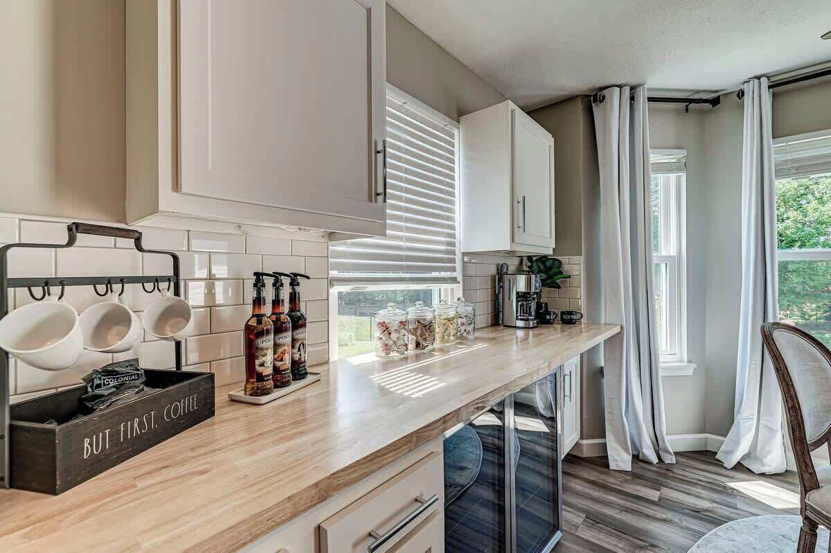 Una cocina moderna con armarios blancos, encimera de madera y una estación de café.