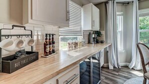 A modern kitchen with white cabinets, a wooden countertop, and a coffee station. - Elegant home in the heart of Westfield! Perfect for family gatherings! (Westfield)