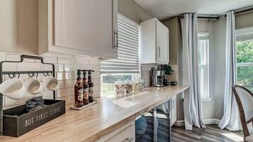 Una cocina moderna con armarios blancos, encimera de madera y una estación de café.