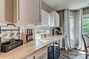 Una cocina moderna con armarios blancos, encimera de madera y una estación de café.