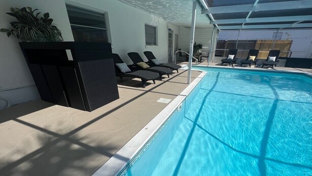 Une piscine avec des chaises longues et un espace abrité.