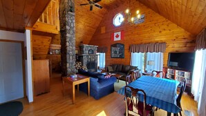 L’intérieur d’un chalet confortable, avec une cheminée en pierre, un plafond en bois et un coin repas.