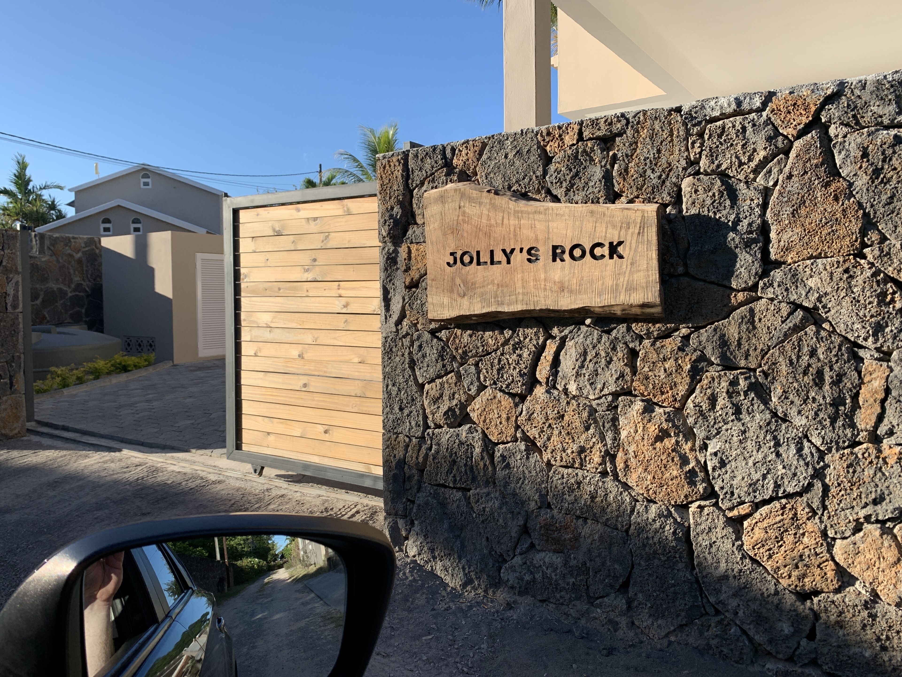A stone wall with a wooden sign that reads "JOLLY'S ROCK".