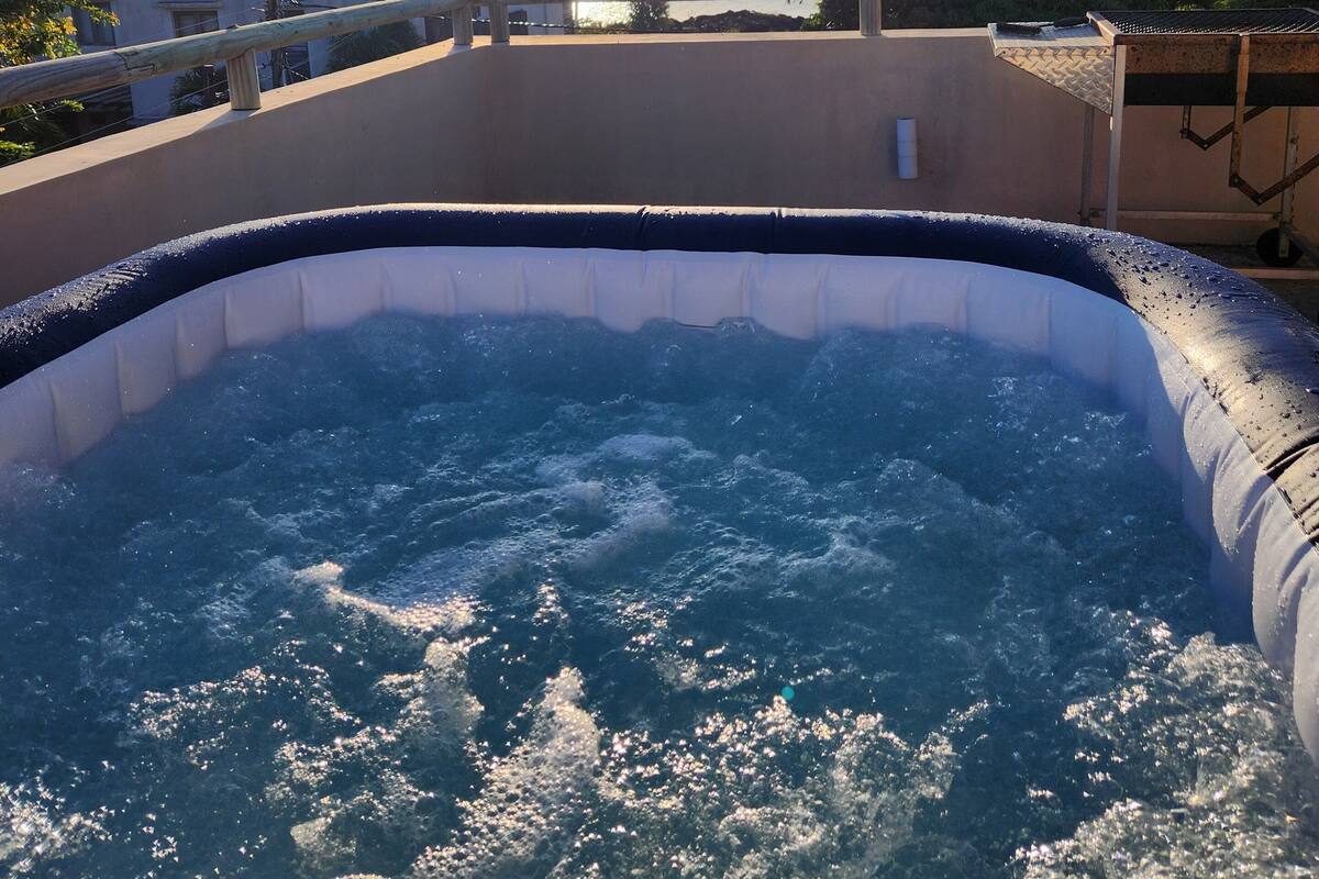 A hot tub with a view of the sea and a sunset in the background.